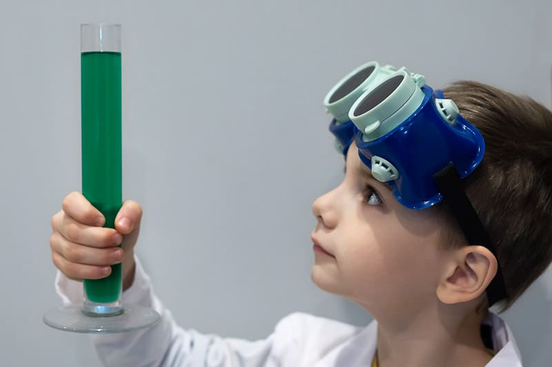 boy in labcoat and goggles with test tube science experement