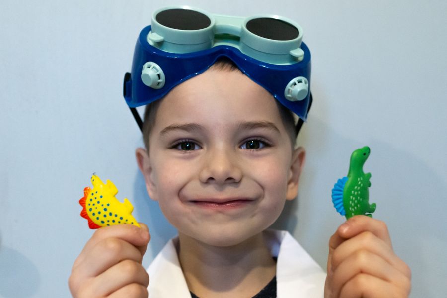 young scientist boy holding toy dinosaurs